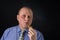 Portrait of mature office clerk smocking tobacco pipe against black background