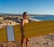 Portrait of mature senior Surfer looking at the ocean with vintage surfboard on an empty beach