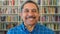 Portrait of mature teacher showing friendly facial expression in school library or community centre. Closeup headshot