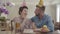 Portrait mature woman and adult grandson talking sitting at the table with birthday cap on their heads. On the table