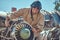 Portrait of a mechanic in uniform and flying helmet, repairing the dismantled airplane turbine in an open-air museum.