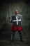 Portrait of medieval warrior, dark skinned bald knight with dirty wounded face holding shield and sword isolated over