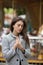 Portrait of melancholy young beautiful brunette woman in a grey coat on a blurry carousel background