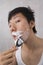 Portrait of mid adult Asian man shaving in bathroom