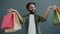 Portrait of middle-aged Arab man holding colorful paper bags with purchases and smiling