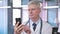 Portrait of Middle Aged Doctor Scrolling on Smartphone