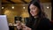 Portrait of middle-aged overweight woman in front of laptop watching into cellphone smilingly on office background.