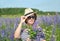 Portrait of a middle-aged woman in a hat and sunglasses among blooming lupins