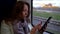 Portrait of a middle-aged woman riding a train sitting at the window and using a mobile phone to communicate on the