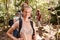 Portrait of millennial white woman with tied up hair hiking in a forest with her friends, close up