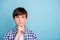 Portrait of minded boy touching chin with his fingers looking dressed in checked shirt  over blue background