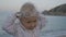 Portrait of mischievous caucasian blonde baby girl wearing glasses for swimming and looking at the sea.