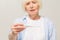 Portrait miserable, sick old woman with allergy, cold, blowing nose with paper tissue, isolated white background. Human face