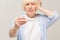 Portrait miserable, sick old woman with allergy, cold, blowing nose with paper tissue, isolated white background. Human face