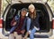 Portrait of mixed race couple sitting in open back of a car