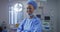 Portrait of mixed race female surgeon wearing lowered face mask smiling in operating theatre