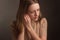 Portrait of a model brown-haired in a white dress on a dark background in the Studio. fastens the earring, hands at the ear