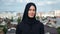 Portrait of modern Muslim young woman in black hijab posing over traditional Islamic city