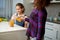 Portrait of a mom pours her cute smiling daughter orange juice for breakfast