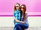 Portrait mother with child girl in checkered shirts, sunglasses in city on colorful pink wall