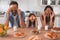 Portrait of mother, daughter and father covering eyes with cookies on the kitchen