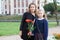 Portrait of mother and schoolgirl going back to school, daughter holding flower