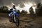 A portrait of motocross rider sitiing on the bike on the background of sunset
