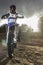 A portrait of motocross rider sitiing on the bike on the background of sunset