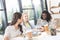 portrait of multiethnic cheerful businesswomen talking while sitting at workplace