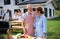 Portrait of multigeneration family outdoors on garden barbecue, grilling.