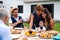 Portrait of multigeneration family sitting at table outdoors on garden barbecue.