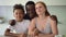 Portrait of multiracial family of three sit at kitchen table, dad kiss mom and son child Spbd. Love