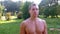 Portrait muscular young sportsman with naked torso in city park after training.