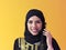 Portrait of muslim woman with headset on yellow background