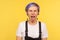 Portrait of naughty hipster woman sticking out tongue and keeping eyes closed. yellow background, studio shot