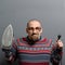 Portrait of a nerdy man holding iron against gray background