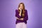 Portrait of nervous insecure cute redhead girl in purple sweater biting fingernails and stooping as feeling scared