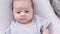 Portrait newborn baby boy lying in nursery cocoon with blue clothes on bed in bedroom at home, happy baby morning.