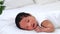 portrait of a newborn black African-American baby with open eyes, a small dark-skinned baby close-up lying on the bed on