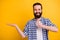 Portrait of nice attractive cheerful cheery confident content bearded guy in checked shirt showing holding invisible