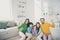 Portrait of nice attractive perfect cheerful family three pre-teen kids mom dad sitting on carpet floor holding in hand