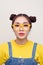 Portrait of nice cute positive pretty cunning Asian girl with two hair-buns, wearing a jeans dungaree