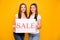 Portrait of nice-looking cute charming lovely attractive cheerful straight-haired girls holding in hands board advice ad