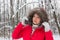 Portrait of a nice senior woman in the winter snow wood in red coat