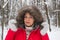 Portrait of a nice senior woman in the winter snow wood in red coat