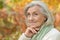 Portrait of nice smiling senior woman posing on blurred autumnal background