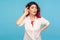Portrait of nosy hipster woman with fancy red hair in shirt listening attentively holding hand near ear to hear confidential talk