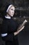 portrait of a nun in black clothes reading the bible and using a rose petal as a bookmark