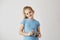 Portrait o good-looking blond child in blue t-shirt smiling, standing with photo camera in hands posing for school album