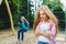 Portrait of offense child at park. On the background other girl riding a swing